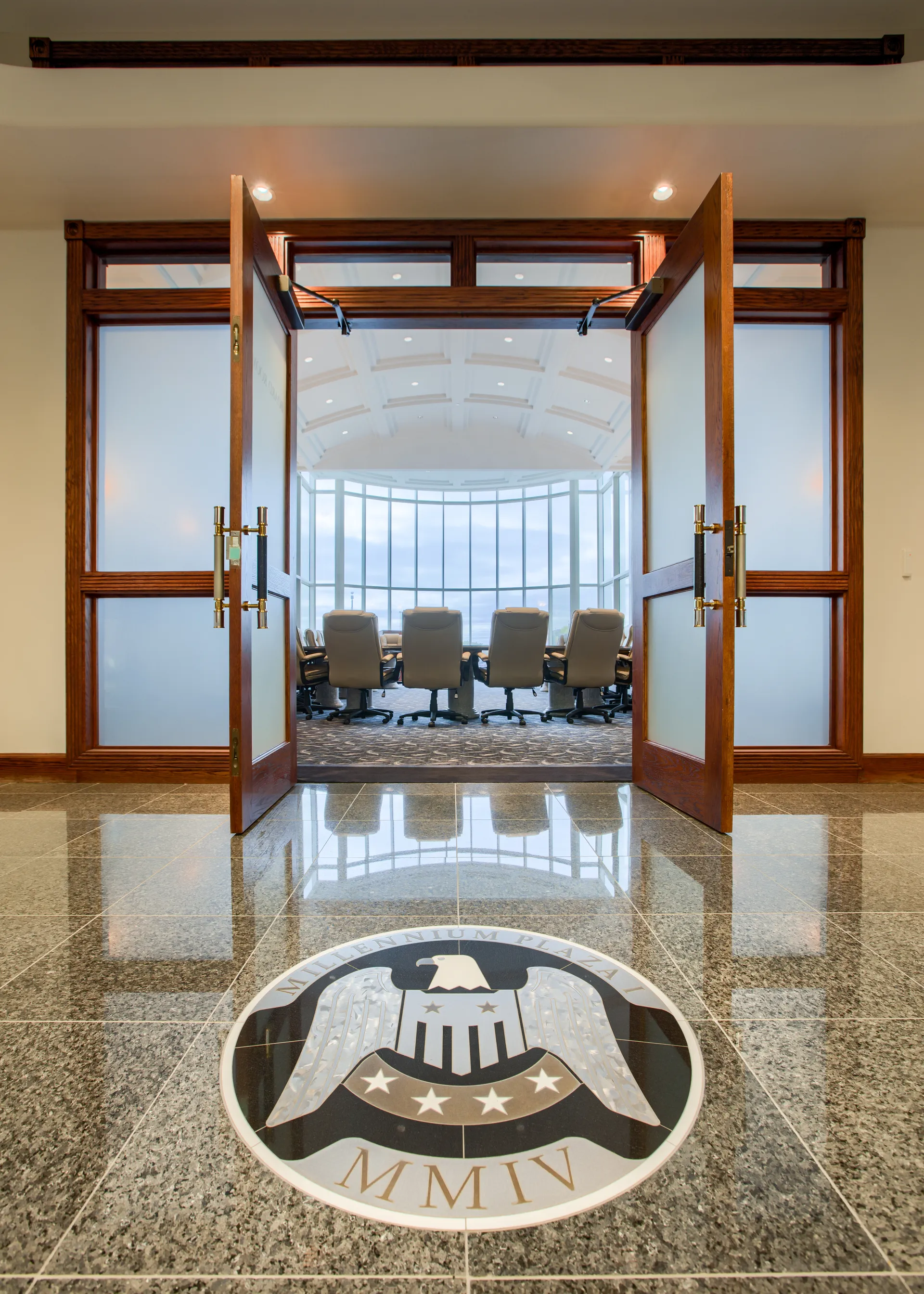 Glass entry doors to the executive board room, framing the eagle medallion inlaid in the lobby floor.