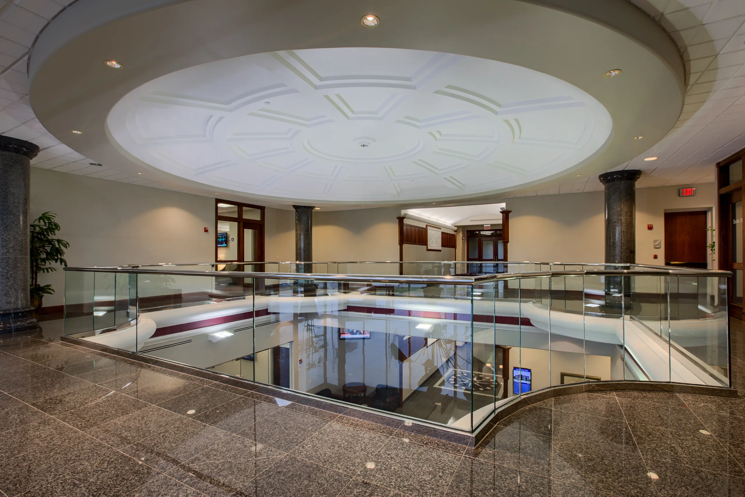Two-story lobby atrium at Millennium Plaza with a domed ceiling and glass railing.